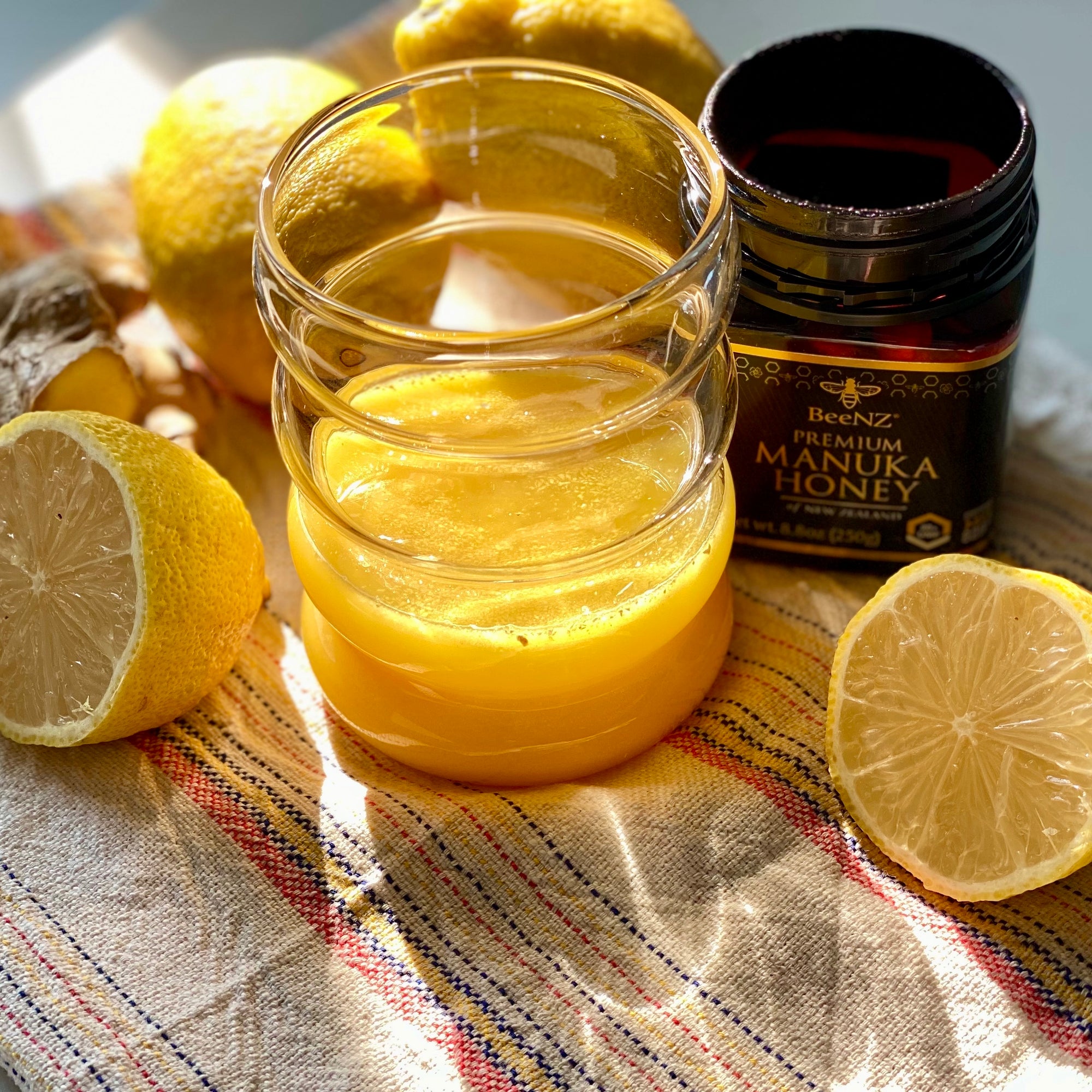 Manuka Honey and Lemon drink in a glass with cut lemons and BeeNZ Honey