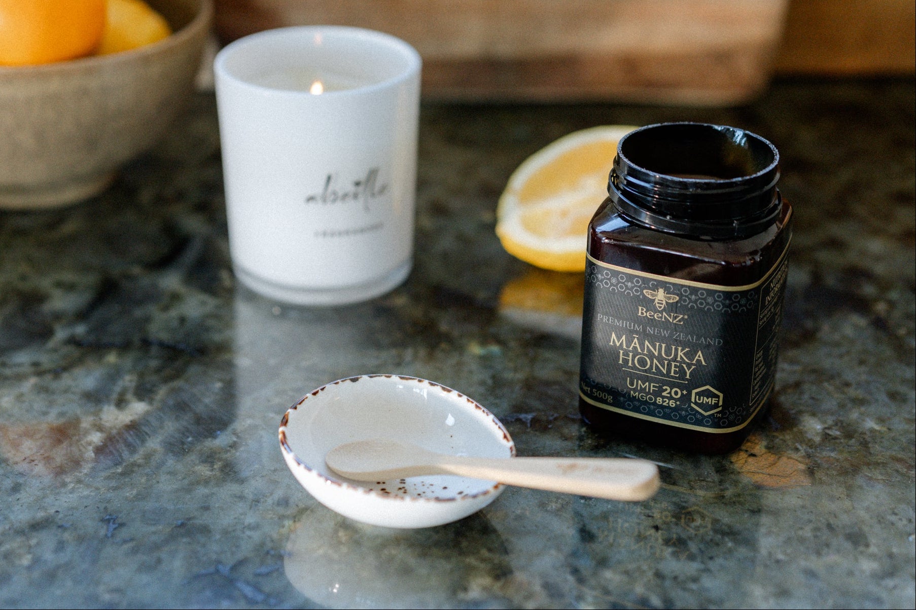BeeNZ manuka honey UMF20+ jar sitting on a bench next to a spoon and dish